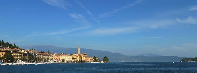Trip Montenegro beliebte Urlaubsziele am Gardasee -  Mit einer Fläche von 370 km² ist der Gardasee der größte See Italiens. Es liegt am Fuße der Alpen und erstreckt sich über drei Staaten: Lombardei, Venetien und Trentino. Die maximale Tiefe des Sees beträgt 346 m, er hat eine längliche Form und sein nördliches Ende ist sehr schmal. Dort ist der See von den Bergen der Gruppo di Baldo umgeben. Du trittst aus deinem gemütlichen Hotelzimmer und es begrüßt dich die warme italienische Sonne. Du blickst auf den atemberaubenden Gardasee, der in zahlreichen Blautönen schimmert - von tiefem Dunkelblau bis zu funkelndem Türkis. Majestätische Berge umgeben dich, während die Brise sanft deine Haut streichelt und der Duft von blühenden Zitronenbäumen deine Nase kitzelt. Du schlenderst die malerischen, engen Gassen entlang, vorbei an farbenfrohen, blumengeschmückten Häusern. Vereinzelt unterbricht das fröhliche Lachen der Einheimischen die friedvolle Stille. Du fühlst dich wie in einem Traum, der nicht enden will. Jeder Schritt führt dich zu neuen Entdeckungen und Abenteuern. Du probierst die köstliche italienische Küche mit ihren frischen Zutaten und verführerischen Aromen. Die Sonne geht langsam unter und taucht den Himmel in ein leuchtendes Orange-rot - ein spektakulärer Anblick.